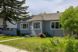 Charming single-family home featuring a welcoming gray exterior and a well-maintained lawn.