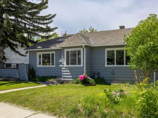Charming single-family home featuring a welcoming gray exterior and a well-maintained lawn.