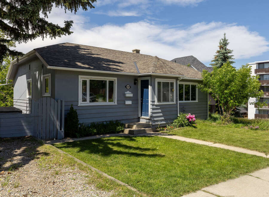 Charming grey bungalow with a welcoming blue front door and pristine white trim.