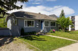Charming grey bungalow with a welcoming blue front door and pristine white trim.
