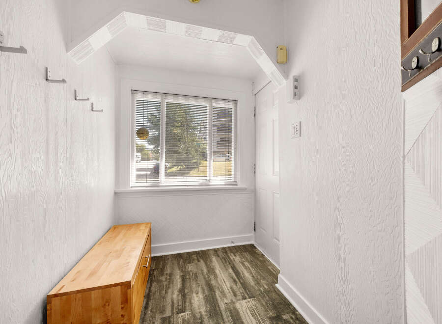 Welcome to this charming entryway, featuring a convenient wooden bench perfect for seating and storage.