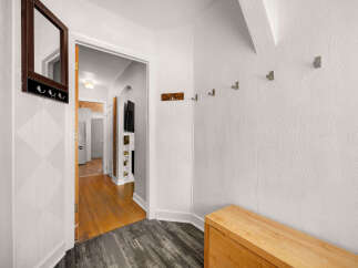 Welcome guests into this charming entryway featuring a decorative mirror with hooks for convenient storage.