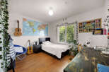 Discover a vibrant and inspiring bedroom featuring a world map, two acoustic guitars, and a cozy reading nook with a blue chair.