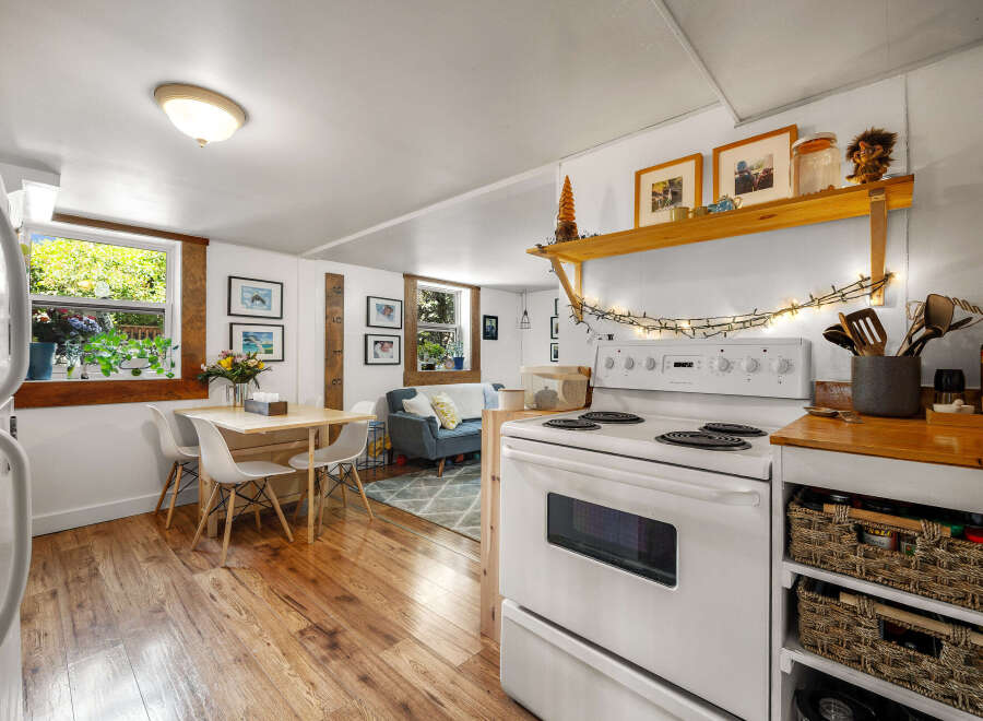 This charming studio apartment features a compact kitchen with a white stove and ample storage in woven baskets.