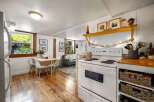 This charming studio apartment features a compact kitchen with a white stove and ample storage in woven baskets.
