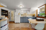 Discover this charming kitchen featuring a bright white refrigerator, sleek gray cabinetry, and a cozy dining area with a light wood table and white chairs.