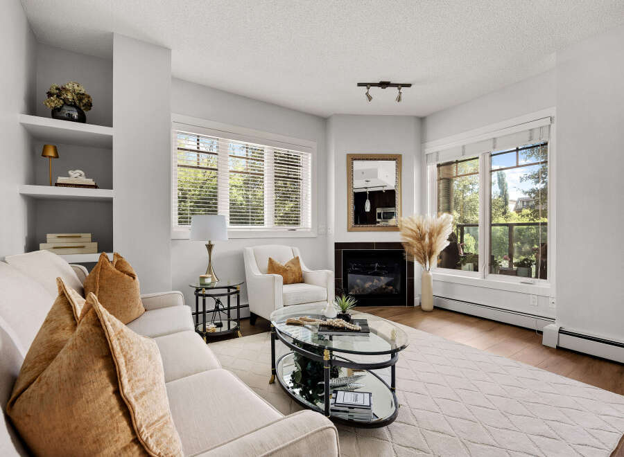 Step into this inviting living room, featuring a plush sofa adorned with warm, textured accent pillows and a cozy armchair perfect for relaxation.
