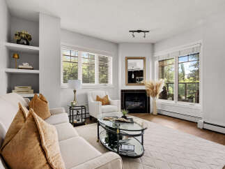 Step into this inviting living room, featuring a plush sofa adorned with warm, textured accent pillows and a cozy armchair perfect for relaxation.