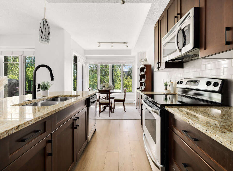 Experience modern living in this stunning kitchen, featuring sleek dark wood cabinetry and elegant granite countertops.