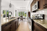 Experience modern living in this stunning kitchen, featuring sleek dark wood cabinetry and elegant granite countertops.
