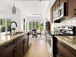 Experience modern living in this stunning kitchen, featuring sleek dark wood cabinetry and elegant granite countertops.