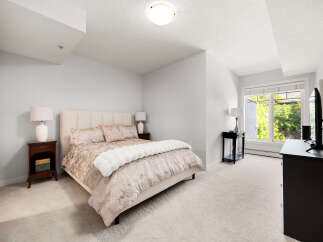 This inviting bedroom features a plush king-sized bed with a textured headboard, complemented by elegant bedside tables and lamps.