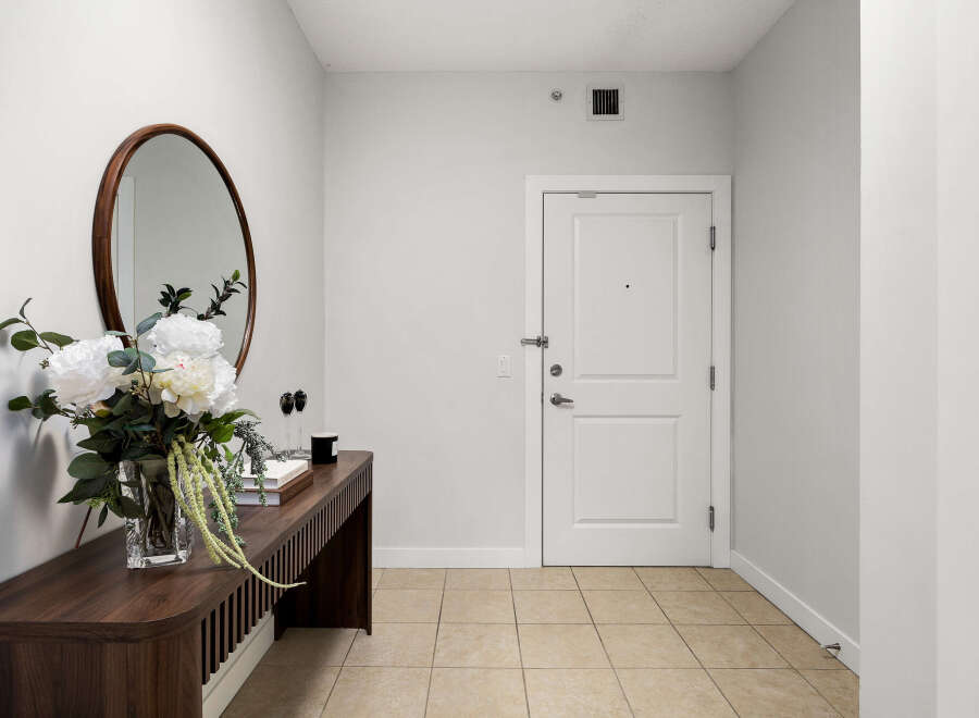 Welcome guests into this inviting entryway featuring a sleek console table adorned with a beautiful floral arrangement and a decorative mirror.