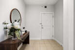 Welcome guests into this inviting entryway featuring a sleek console table adorned with a beautiful floral arrangement and a decorative mirror.