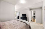 This bedroom offers a serene retreat with a plush bed and a modern entertainment setup.