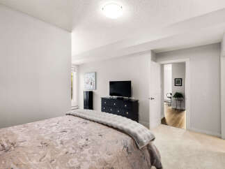 This bedroom offers a serene retreat with a plush bed and a modern entertainment setup.
