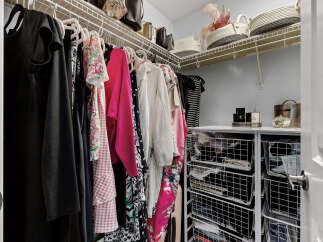 Discover organized living in this spacious walk-in closet, featuring ample hanging space for your wardrobe and convenient wire basket storage for accessories.