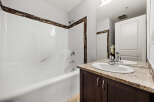 This bathroom features a pristine white bathtub with a decorative mosaic tile accent along the top edge, complemented by a sleek chrome showerhead and faucet.