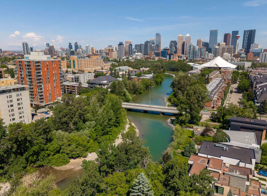 Experience urban living with a touch of nature in this stunning aerial view of a vibrant city skyline bordering a serene river.