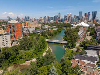Experience urban living with a touch of nature in this stunning aerial view of a vibrant city skyline bordering a serene river.