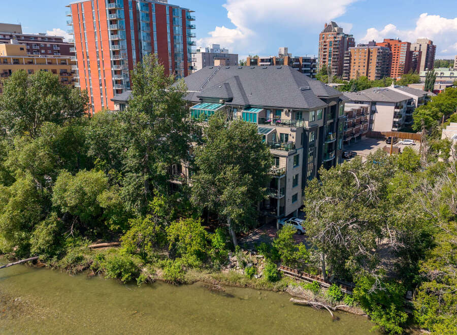 Experience luxury living with this stunning property featuring a modern condo building nestled beside a serene river.