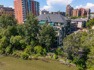 Experience luxury living with this stunning property featuring a modern condo building nestled beside a serene river.