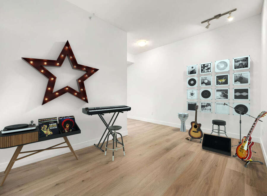 This stylish room is a music lover's dream, featuring a vintage-inspired record player console, a digital keyboard, and a collection of vinyl records displayed as art.