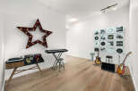 This stylish room is a music lover's dream, featuring a vintage-inspired record player console, a digital keyboard, and a collection of vinyl records displayed as art.