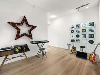 This stylish room is a music lover's dream, featuring a vintage-inspired record player console, a digital keyboard, and a collection of vinyl records displayed as art.
