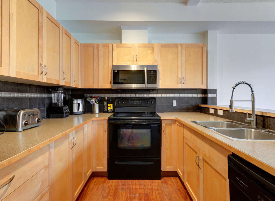Discover this beautifully appointed kitchen featuring sleek light wood cabinetry and a modern stainless steel microwave.