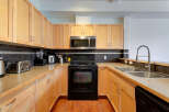 Discover this beautifully appointed kitchen featuring sleek light wood cabinetry and a modern stainless steel microwave.