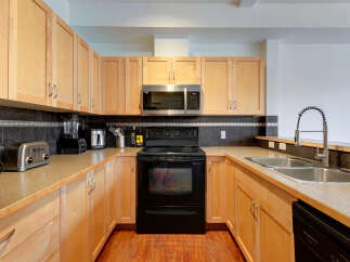 Discover this beautifully appointed kitchen featuring sleek light wood cabinetry and a modern stainless steel microwave.