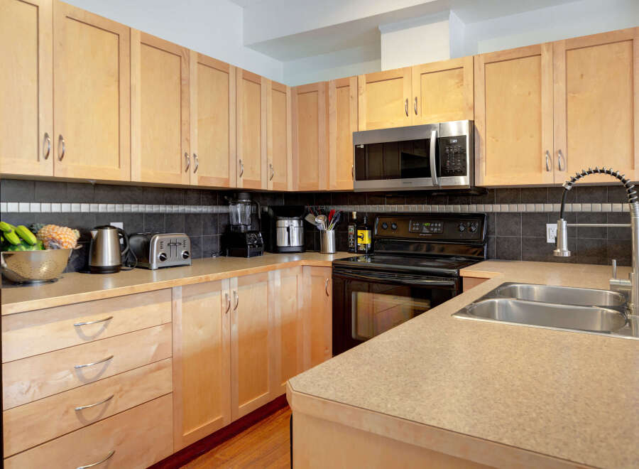This kitchen boasts modern light wood cabinetry and sleek countertops, offering ample storage and workspace.