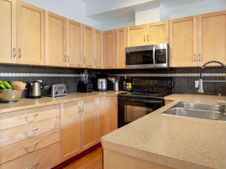 This kitchen boasts modern light wood cabinetry and sleek countertops, offering ample storage and workspace.