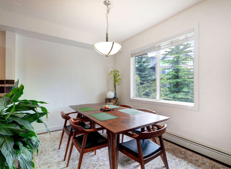 Enjoy meals in this charming dining area, featuring a rich wooden table set with green placemats and elegant chairs.