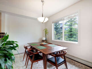 Enjoy meals in this charming dining area, featuring a rich wooden table set with green placemats and elegant chairs.