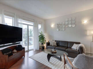 Experience modern living in this stylish living room, featuring a sleek dark leather sofa and a contemporary glass coffee table.