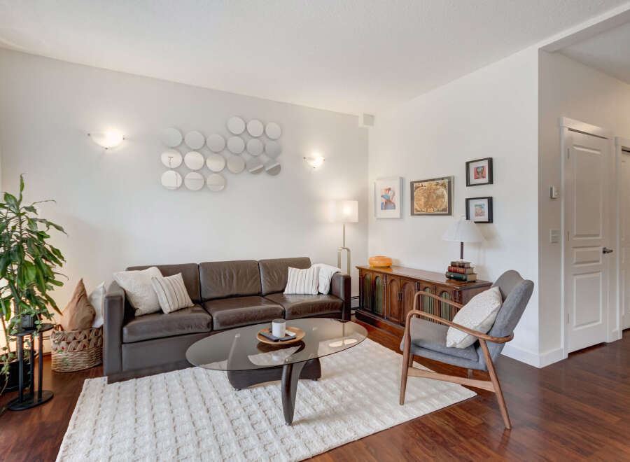 Step into this inviting living room, featuring a rich brown leather sofa complemented by a plush white rug and a sleek glass coffee table.