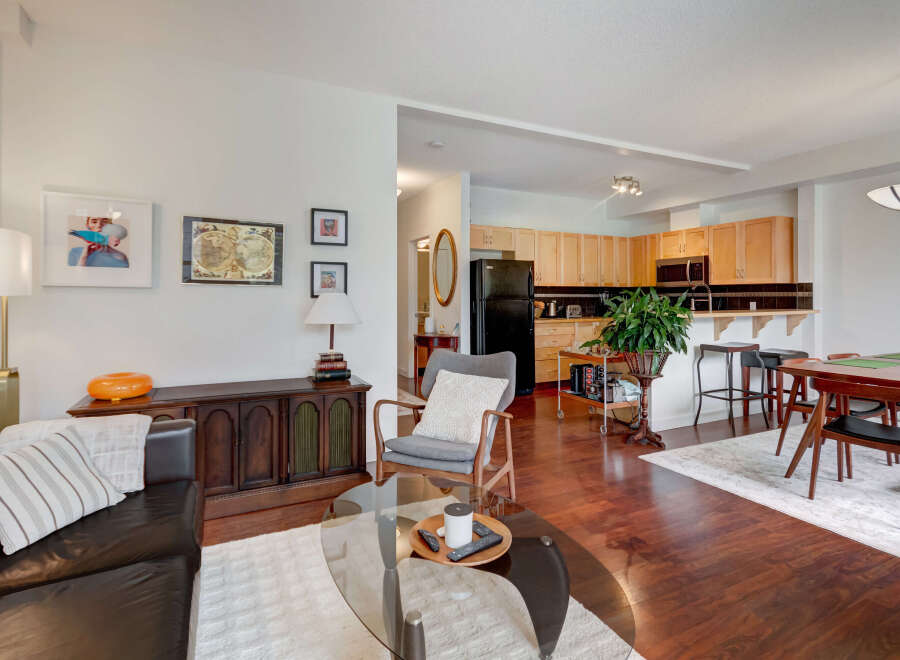 This open-concept living space features a modern kitchen with light wood cabinetry and a breakfast bar, seamlessly flowing into a comfortable living area.