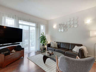 Experience modern living in this stylish living room, featuring a sleek dark leather sofa and a contemporary glass coffee table.