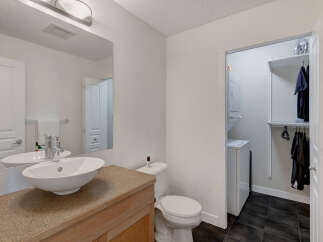 This modern bathroom features a sleek vanity with an undermount sink and a chrome faucet, complemented by a large mirror reflecting a clean white door.