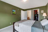 This inviting bedroom features a spacious bed with comfortable bedding, complemented by a serene green accent wall.