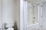 This bathroom features a pristine white toilet and a modern shower/tub combination with a sleek chrome showerhead and faucet.