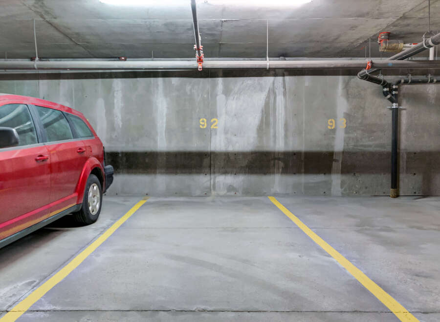 Discover convenient and secure parking at this property, featuring a spacious red SUV parked in a designated spot.