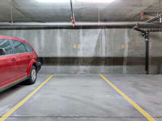 Discover convenient and secure parking at this property, featuring a spacious red SUV parked in a designated spot.