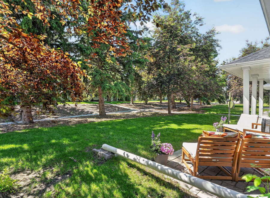 Enjoy outdoor living in this beautifully landscaped backyard, featuring a lush green lawn perfect for recreation and mature trees providing ample shade.