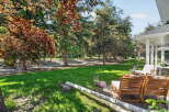 Enjoy outdoor living in this beautifully landscaped backyard, featuring a lush green lawn perfect for recreation and mature trees providing ample shade.