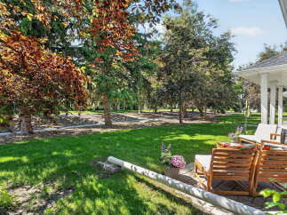 Enjoy outdoor living in this beautifully landscaped backyard, featuring a lush green lawn perfect for recreation and mature trees providing ample shade.