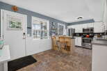 This charming kitchen features white cabinetry, stainless steel appliances, and a convenient breakfast bar with seating.