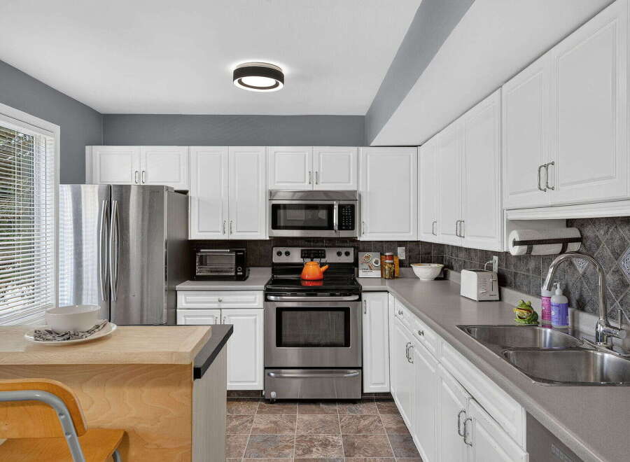 This spacious kitchen features sleek stainless steel appliances, including a refrigerator, microwave, and oven.